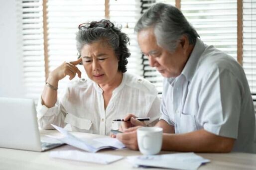 A senior couple looks at their retirement savings on a laptop.